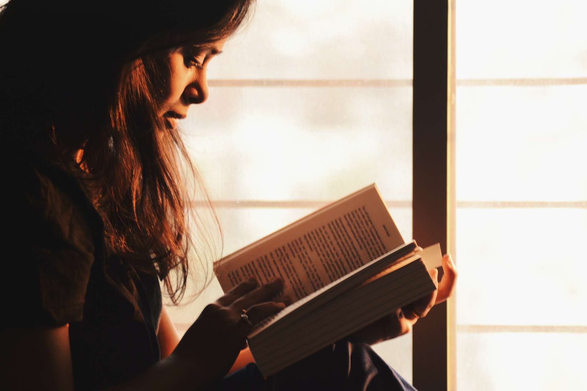 A girl reading by the light of a window