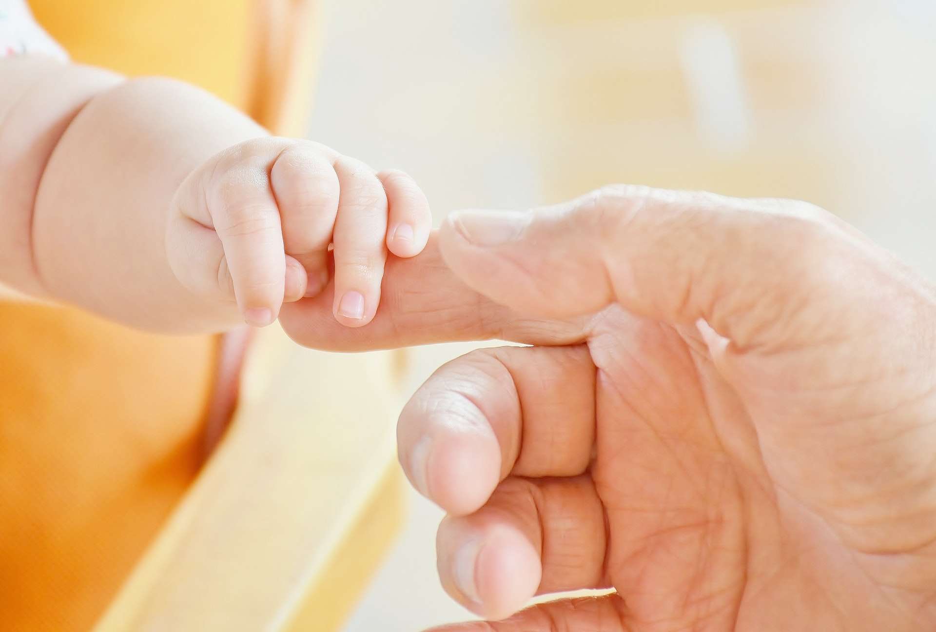 an infant holding a mans finger