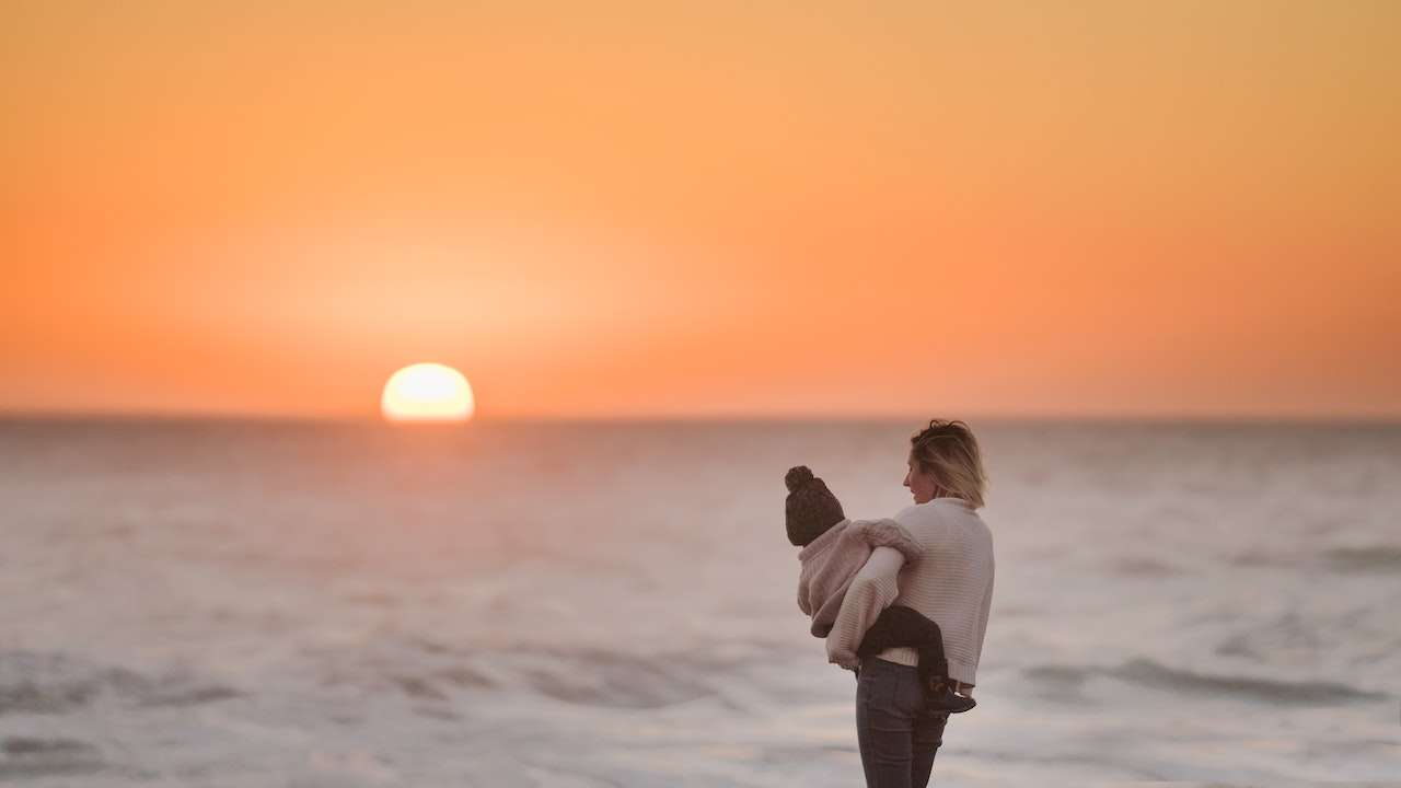 mother and child at sunset on the beach. choose god